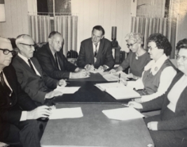 1967 black and white image of men and women gathered at a long table to discuss the development of Rockridge.