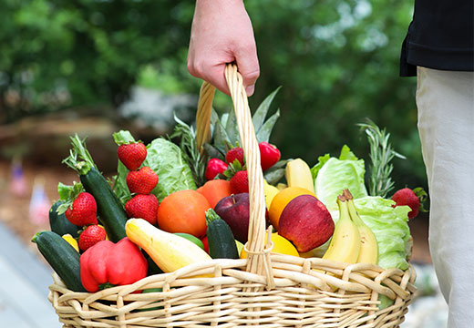 A man holding a basket full of fresh vegetables and fruits.